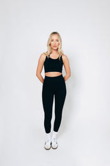 Model wearing a black ribbed leggings and bralet set from sosala