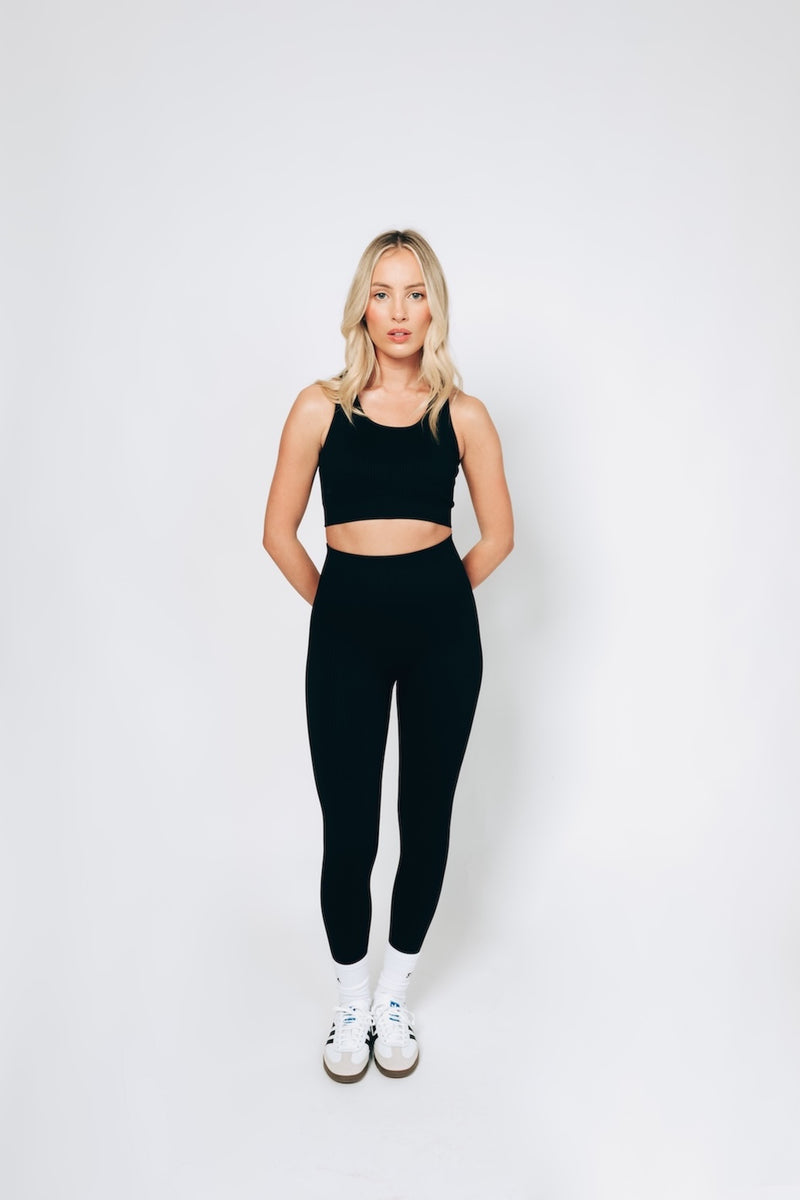 Model wearing a black ribbed leggings and bralet set from sosala