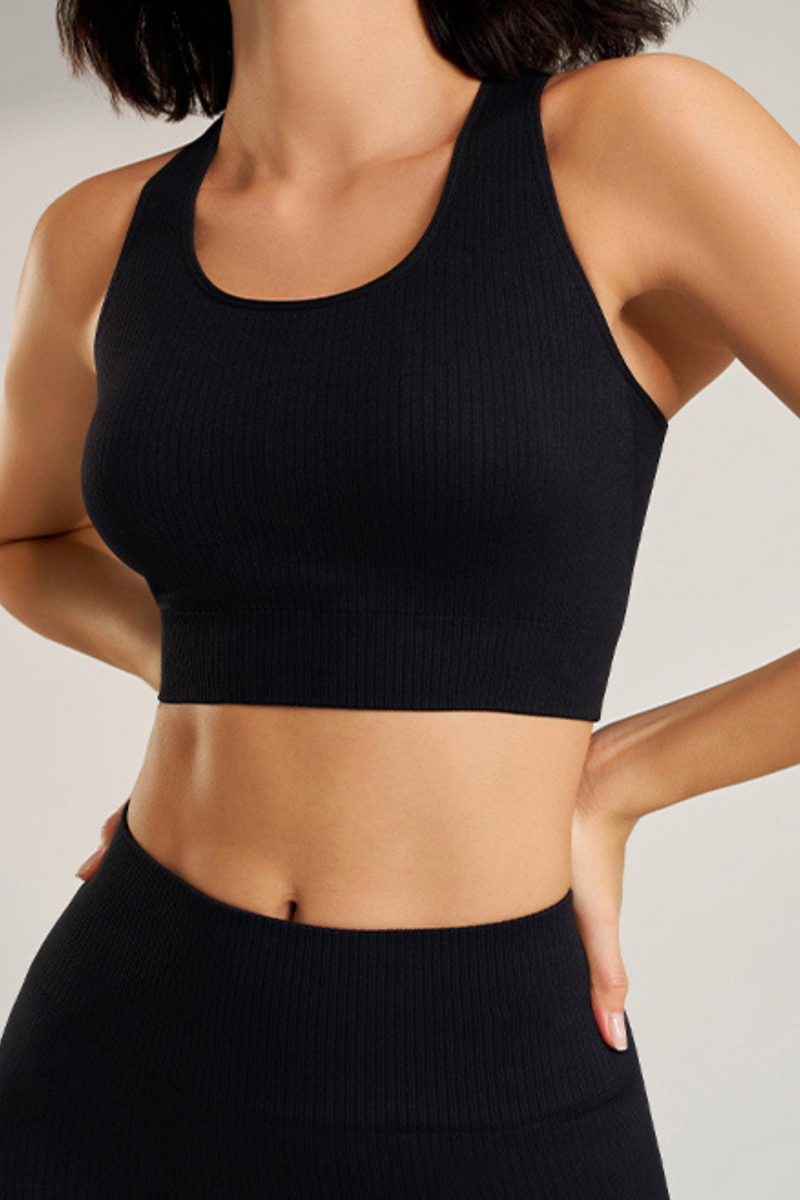 Person wearing a black ribbed sports bra and leggings sosala set on a light gray background