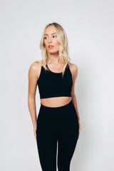 A female model wearing a black ribbed racerback bralet and high-waisted leggings set from sosala 