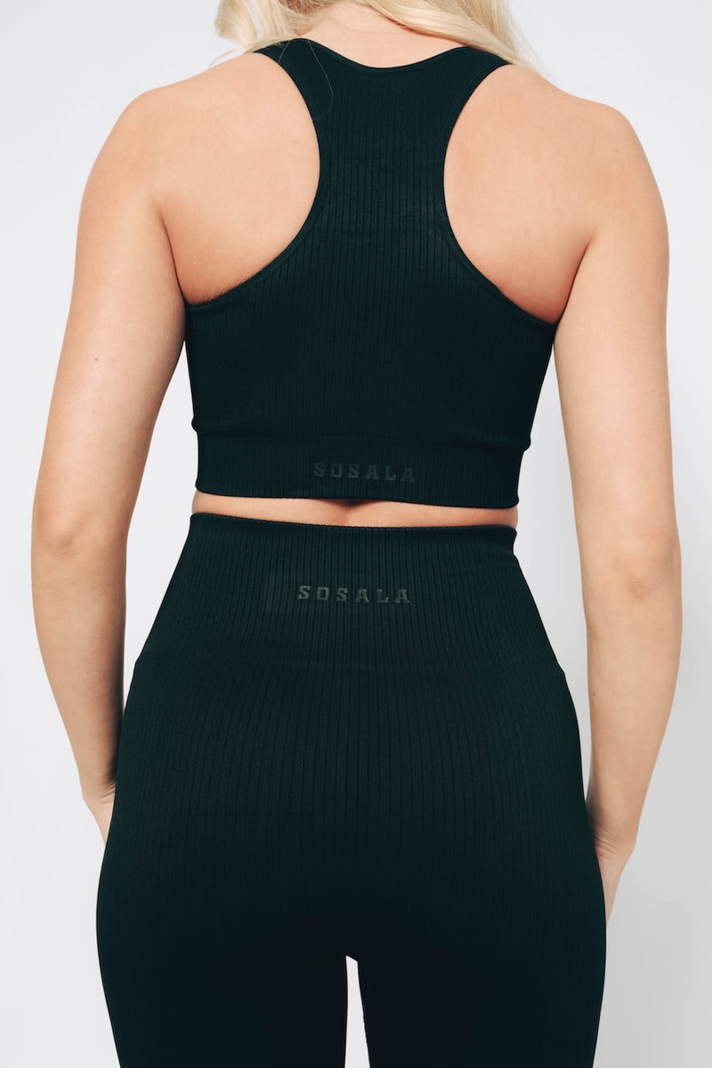 A model wearing a black ribbed fabric racerback bralet and high-waisted leggings sosala set, both with a smooth, solid pattern.