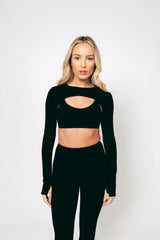 A model wearing a long-sleeved black crop top with a cut-out area at the front, made from buttery-soft, breathable fabric.
